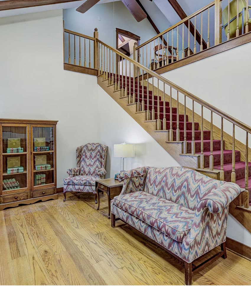 Cozy living area featuring patterned sofas, armchairs, and a wooden staircase.