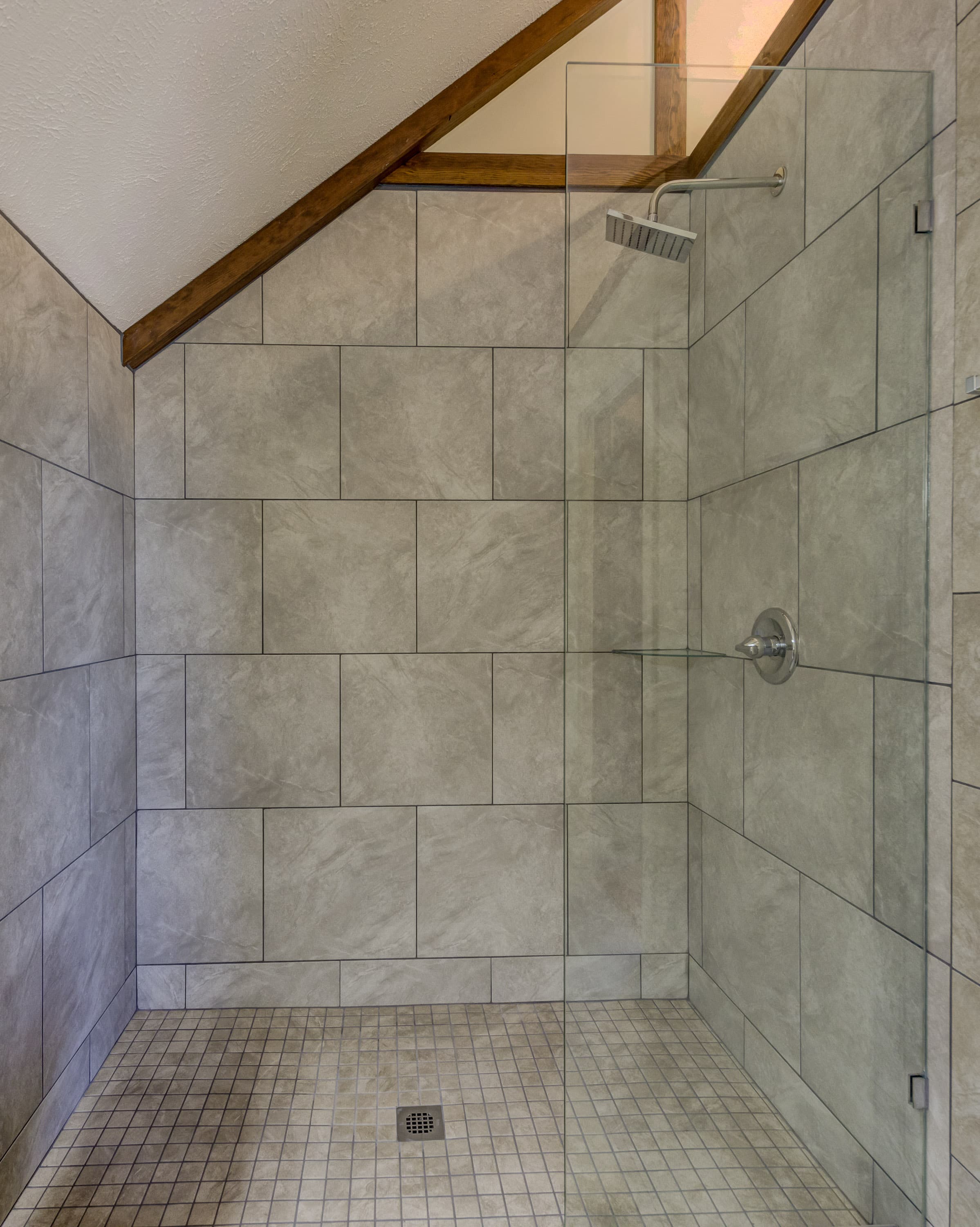 A modern shower with glass walls and gray tiled surfaces.