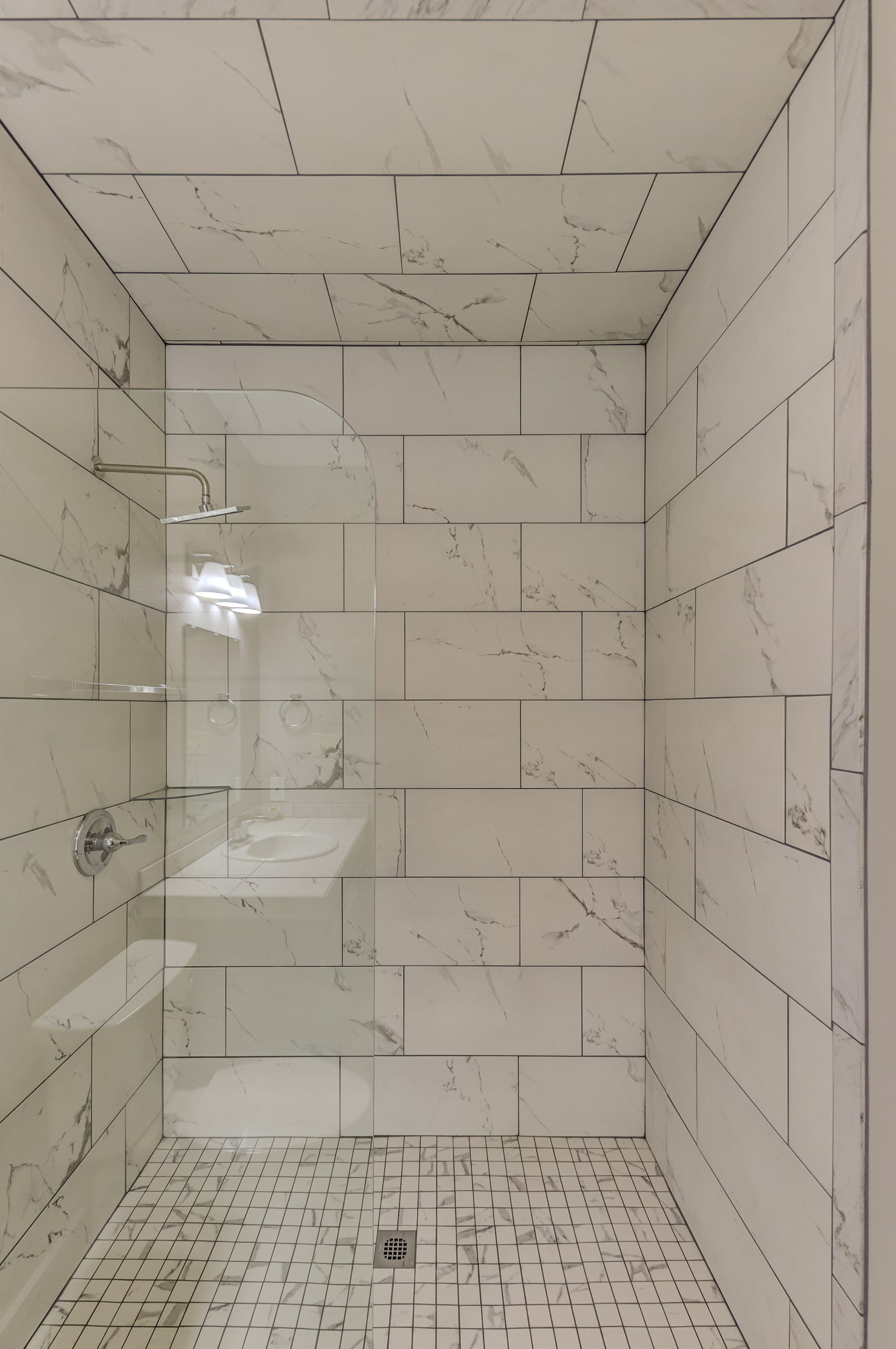 Modern shower enclosure with marble tiles and a glass door.